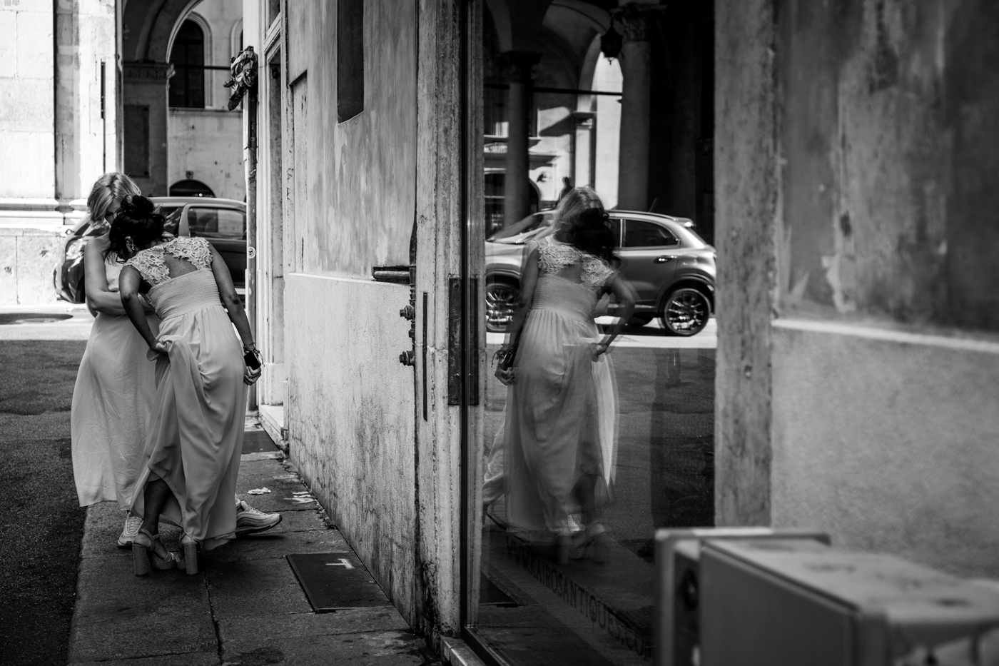 ragazza si sistema il vestito con riflesso nella vetrina