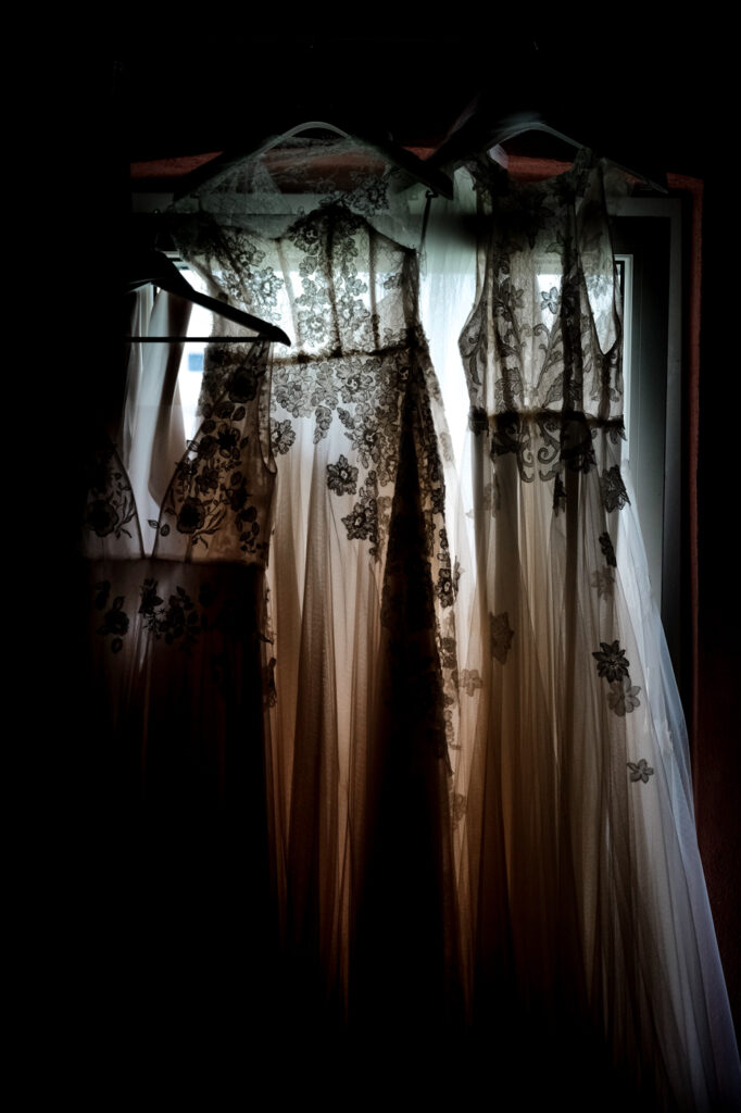 Tre abiti da sposa con fiori appesi a una finestra